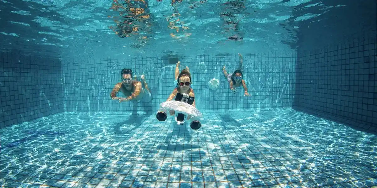 Three people underwater in the pool with Sublue Whiteshark Mixpro.