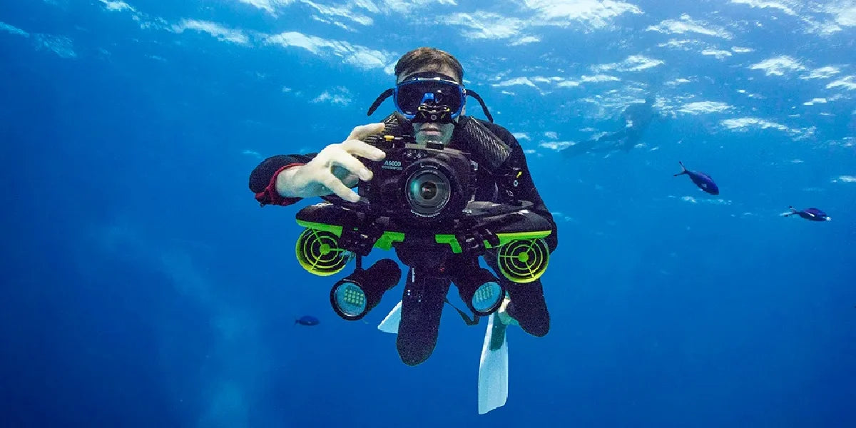 Diver using Navbow Sublue underwater scooter with photography gear.