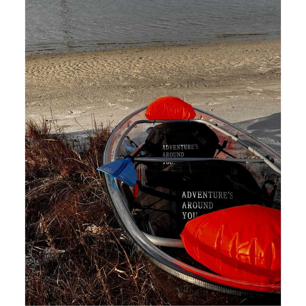 Adventurer Aura Kayaking transparent canoe on the beach facing water.