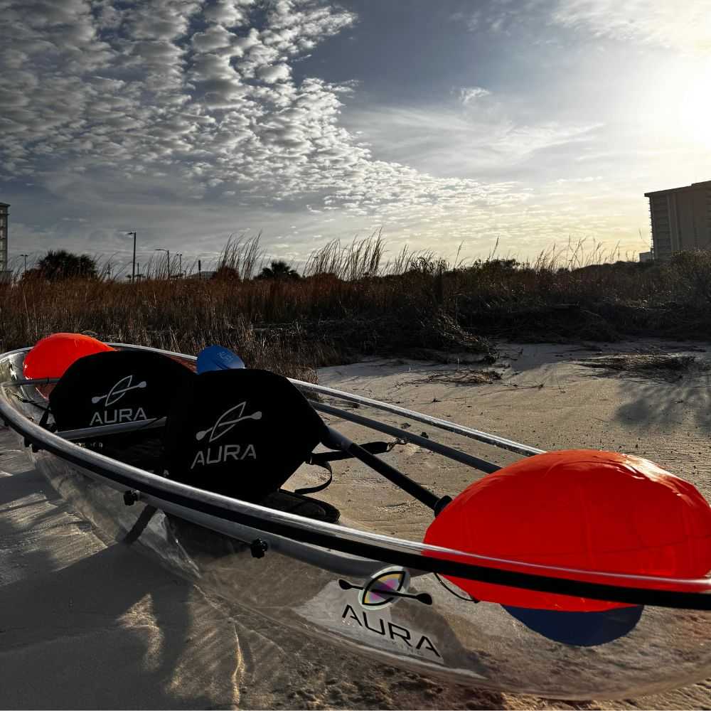 Kayaking Aura Adventurer see-through canoe on the beach with sunset in background.