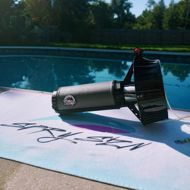 Dive Xtras Blacktip Travel Underwater Scooter on towel next to pool outside.