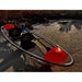 Kayaking Aura Adventurer transparent kayak on beach with paddle inside.