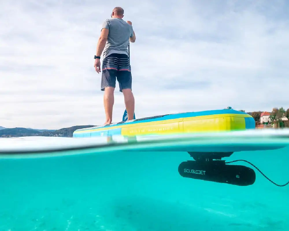 Scubajet Pro underwater scooter mounted to bottom of paddleboard with adult on top.