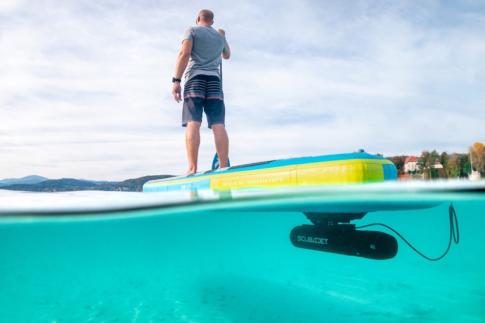 Adult paddleboarding with SCUBAJET PRO SUP Kit underwater scooter installed.