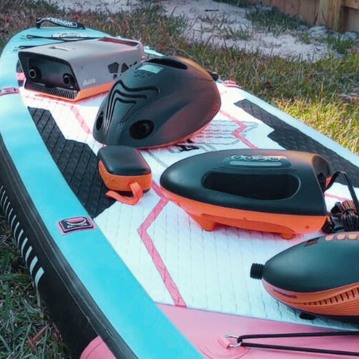 What Outdoor Master electric SUP pump should I buy? Four pumps and one portable power bank on top of a WOWSEA Poseidon P1 Inflatable and affordable paddle board with the SPRY SZN logo on the bottom left.